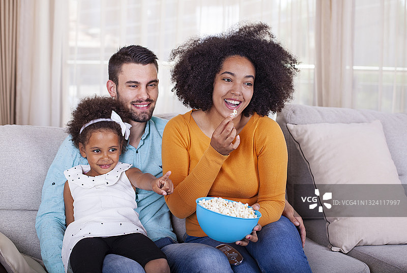 快乐的非裔美国人家庭看电视吃爆米花图片素材
