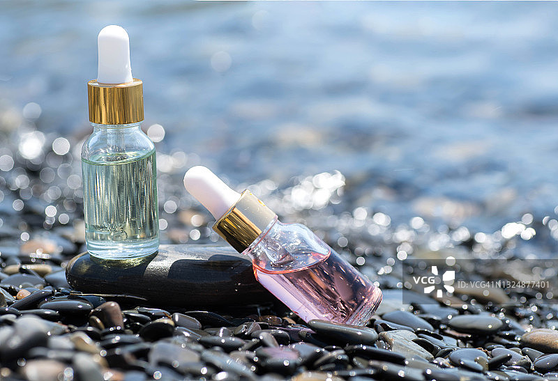 美丽的瓶子与海洋胶原蛋白血清在海石与阳光刺眼图片素材