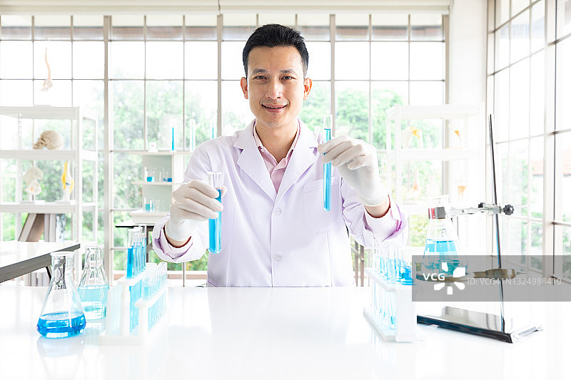 肖像科学家男子与蓝色酒精化学实验在实验室图片素材