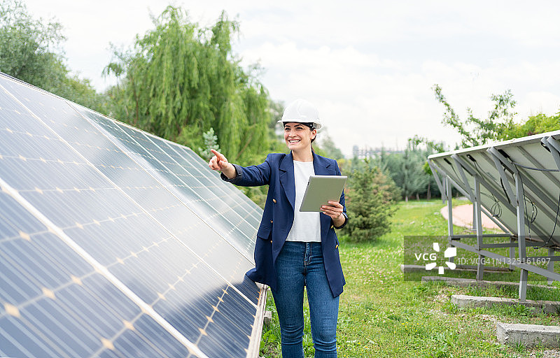 女经理工程师İn安全帽平板检查太阳能电站太阳能电池板系统的操作图片素材