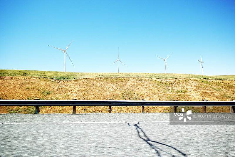 公路后面山坡上的风力涡轮机图片素材