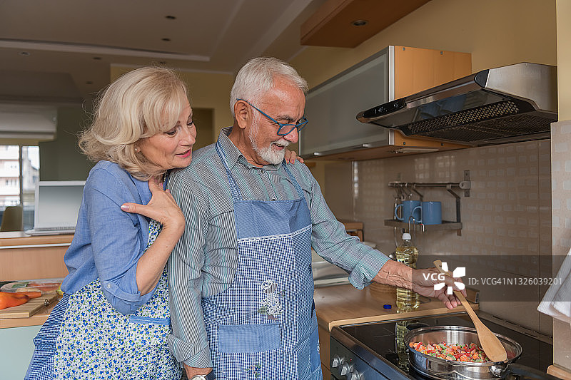 快乐的老年配偶享受空闲时间在家做饭午餐。图片素材