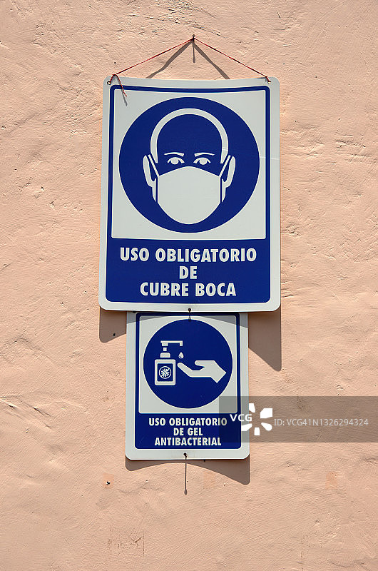 一家企业的灰泥墙上贴着西班牙语covid-19健康和安全标识图片素材