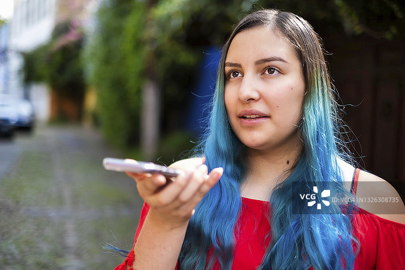 一个蓝头发的拉丁姑娘用手机发了一条语音信息图片素材