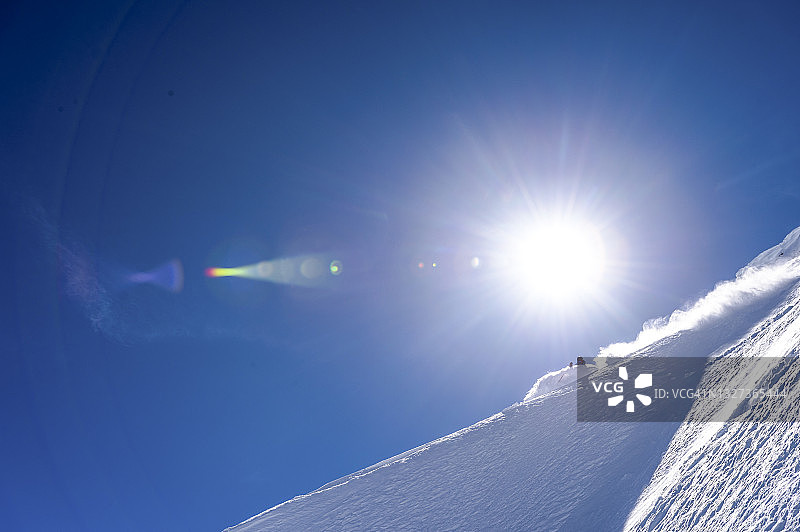 偏远地区的滑雪者从雪山山脊上滑下来图片素材