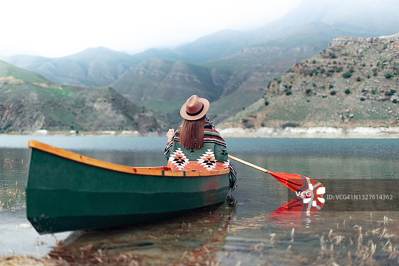 戴着帽子在湖上划独木舟的年轻女子图片素材