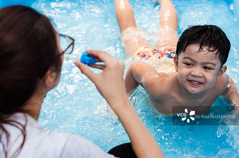 来自东南亚的母亲和儿子在充气游泳池里玩耍图片素材