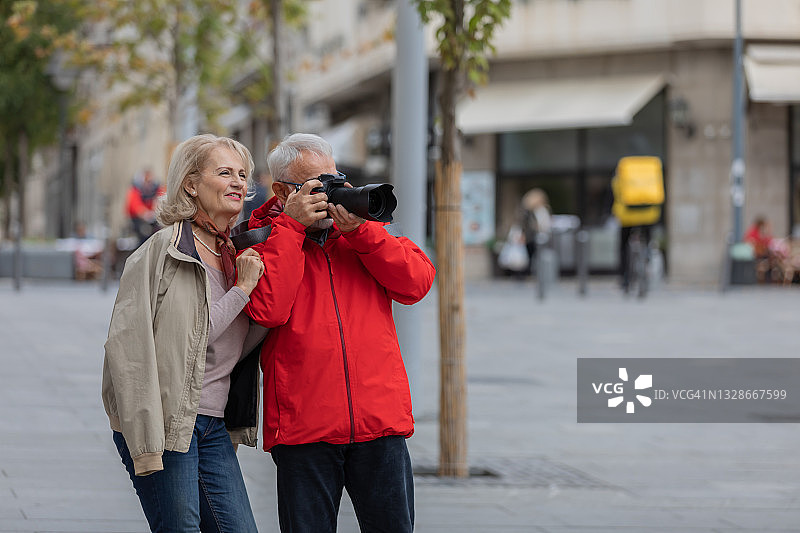 一对老年游客在享受假期的同时，探索城市，用相机捕捉瞬间。图片素材