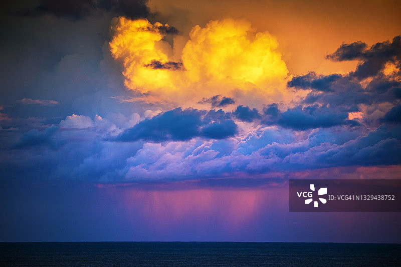紫色的雨，橙色和蓝色的海上风暴云图片素材