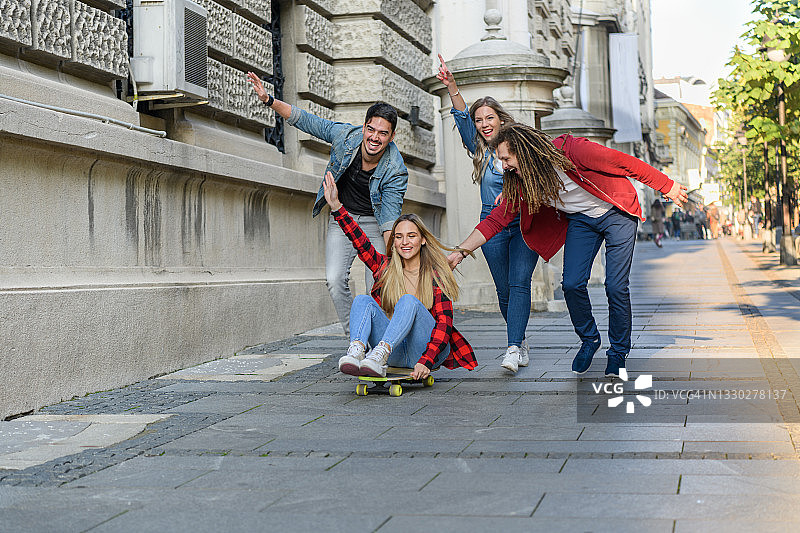 一群年轻的朋友在城市里玩滑板享受假期。图片素材