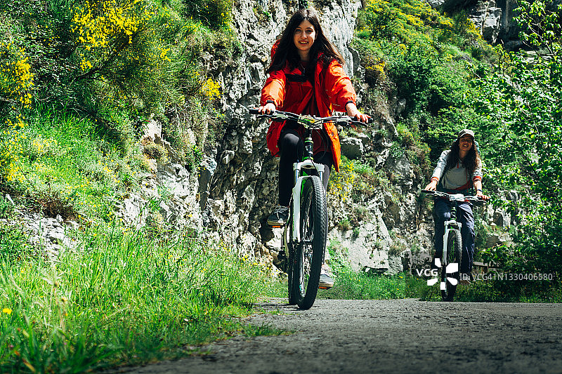 两名年轻女子在一条自然路线上骑山地自行车图片素材