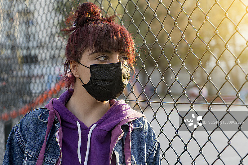 一名戴着口罩的年轻女子被困在隔离区covid-19，冠状病毒图片素材