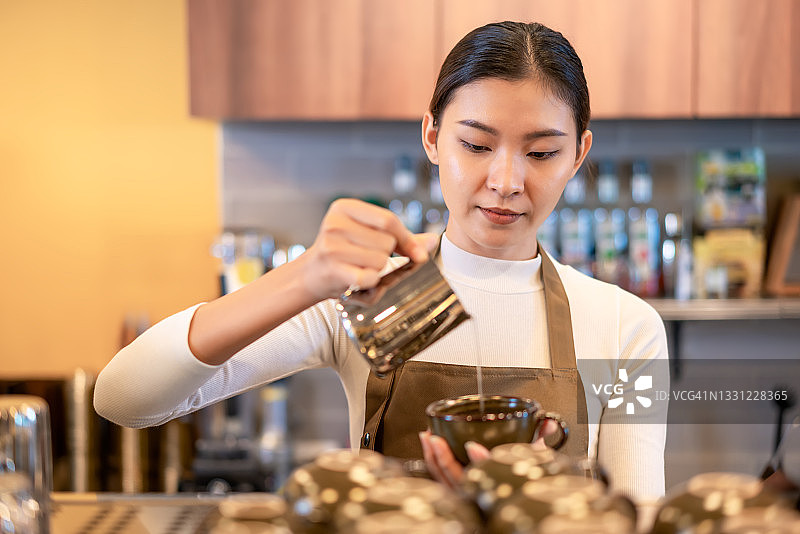 亚洲女咖啡师将水倒进咖啡杯在柜台柜台前的机器，喝企业主的概念图片素材