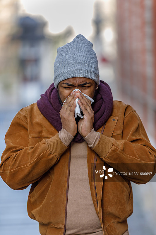 患有季节性过敏的非洲裔美国人正在用纸巾擤鼻子。图片素材