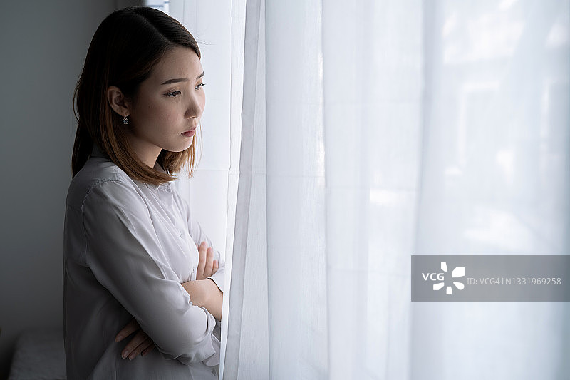 有压力的亚洲女人，她把自己一个人留在卧室里，抑郁。图片素材