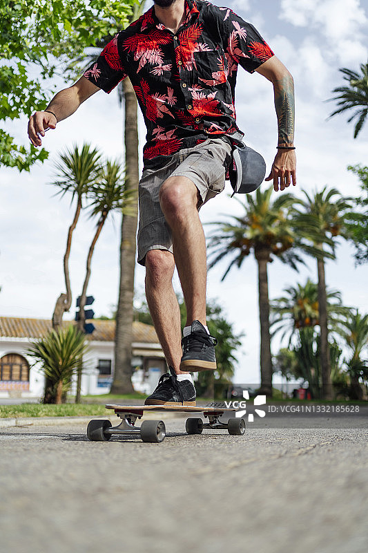 男子在路上玩滑板时保持平衡图片素材