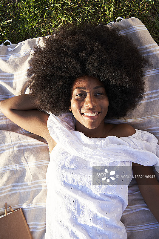 微笑的非洲年轻女子躺在公园图片素材