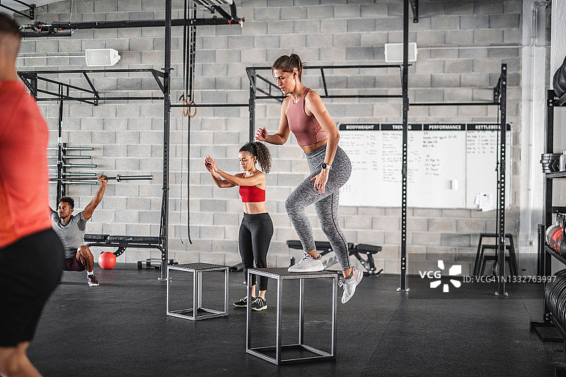 20多岁的女运动员在健身房做箱子跳跃图片素材