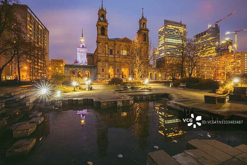波兰，马索维亚，华沙，教堂和城市摩天大楼在夜晚的池塘倒影图片素材
