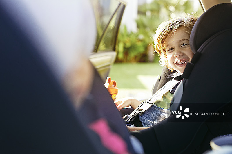 可爱的男孩坐在车里微笑图片素材