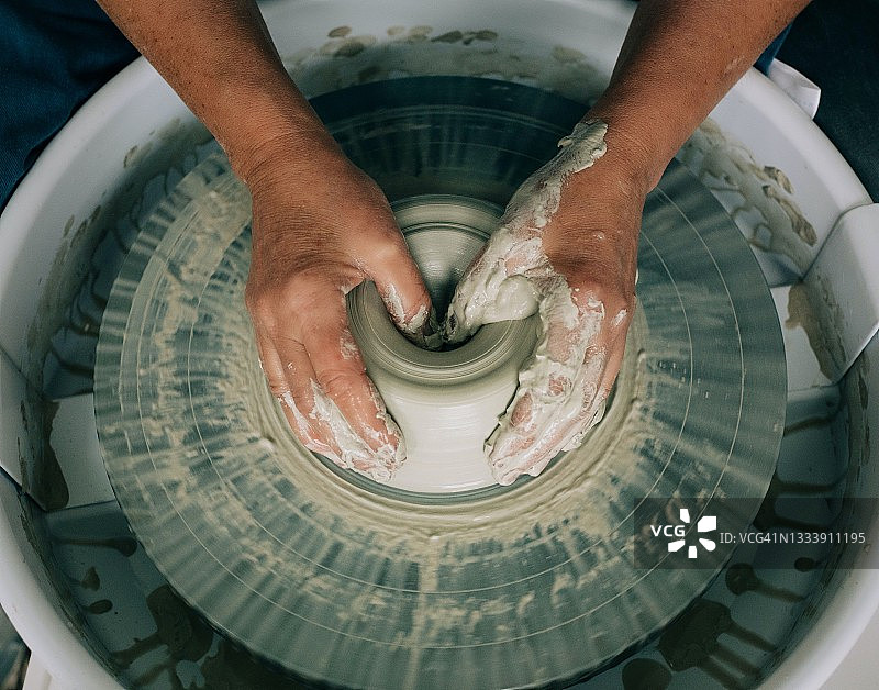 在工作室里，双手凌乱地在轮子上制作陶器图片素材