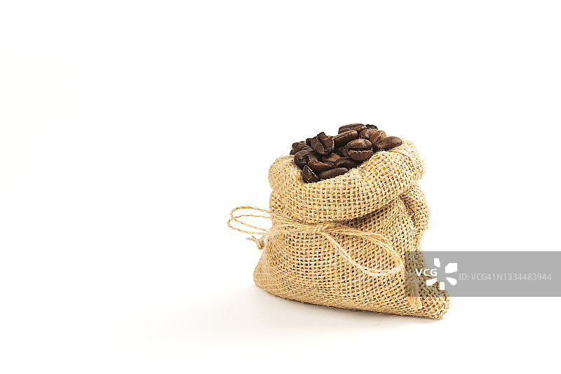 黑色背景下的咖啡杯和麻袋里的烤咖啡豆。图片素材