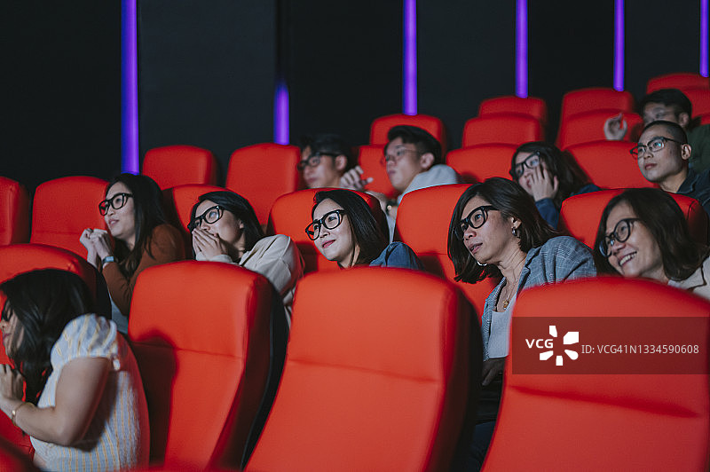 一群亚洲华人观众在电影院观看3D电影，戴着3D眼镜享受着表演，尖叫着兴奋图片素材