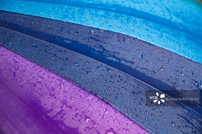 雨滴在蓝色紫色遮阳伞上特写湿织物纹理图片素材