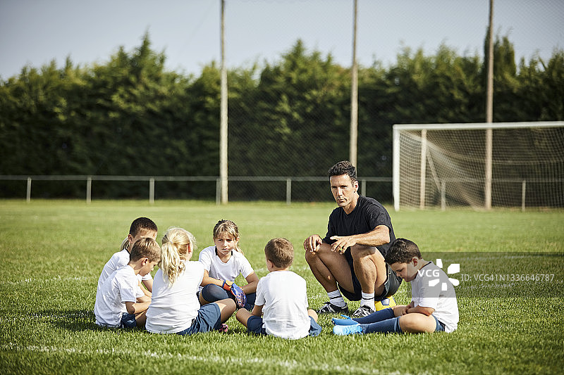 足球教练在球场上对孩子们说话图片素材
