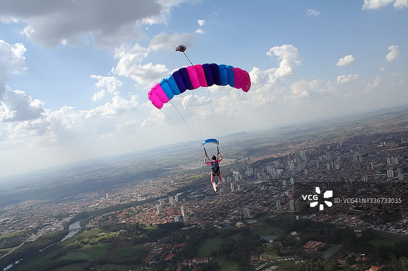 跳伞者用降落伞飞过城市上空图片素材
