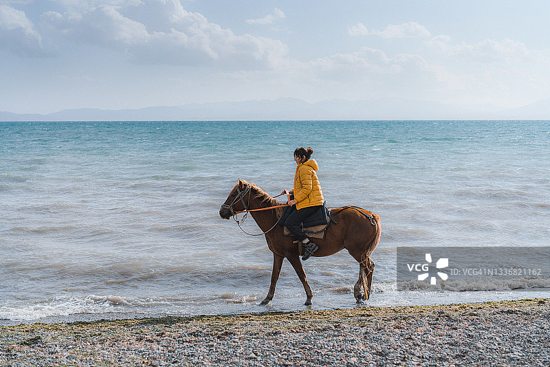 在吉尔吉斯斯坦的孙古尔湖附近，一名女子骑着马图片素材
