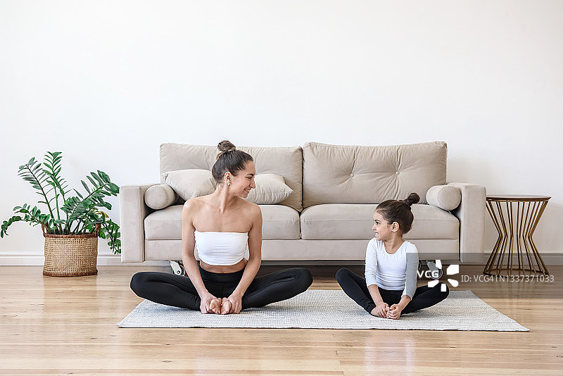 快乐的妈妈和女儿在家做瑜伽伸展运动图片素材
