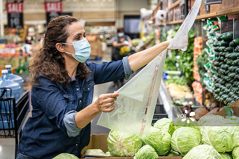 在超市购买有机蔬菜的成年女性戴着防护口罩图片素材