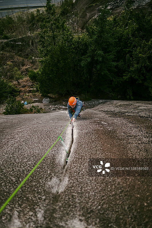 在公元前斯夸米什，一名年轻女子正在攀登一条垂直的花岗岩裂缝图片素材