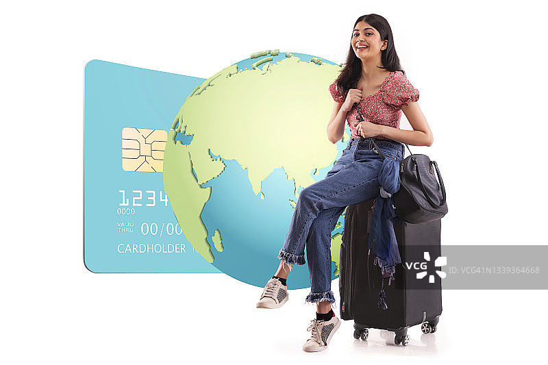 一个年轻的女人坐在她的行李与全球网络银行图形。图片素材