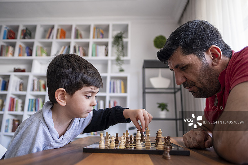 父亲和儿子一起在家里下棋。家人在家里。图片素材