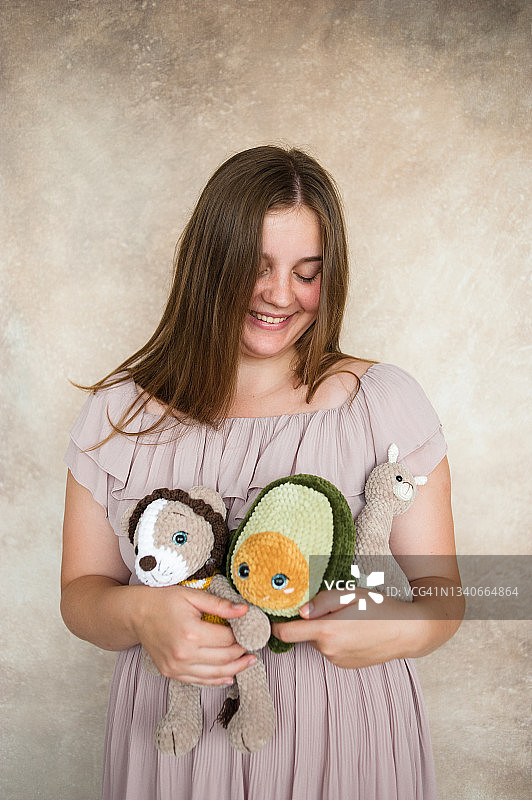 一个美丽的年轻女子的肖像，谁是钩针阿米古umi玩具的大师，手里拿着她的针织物品。图片素材