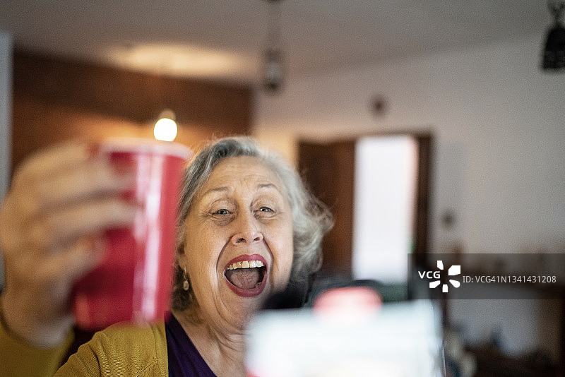 在家中聚会时，一位年长的女性被人用智能手机拍摄或拍照图片素材
