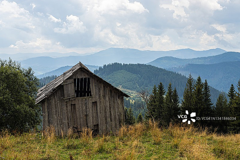 山上废弃的建筑，岩石背景下的木屋，自然景观，绿色的草地和森林图片素材