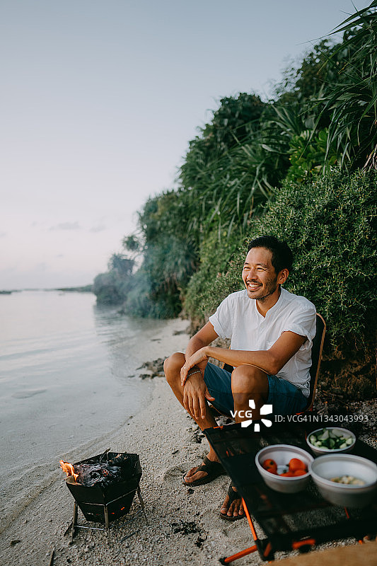 日本，Amami，日落时分，一名男子在海滩上享受篝火图片素材