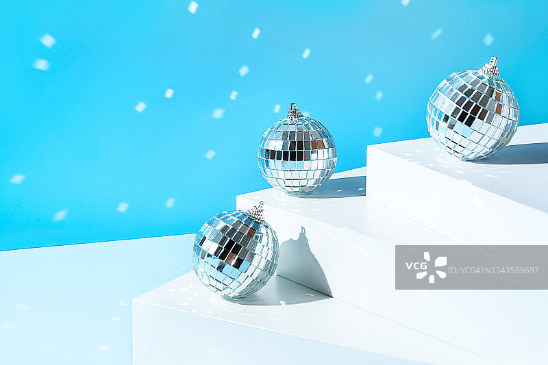 银色迪斯科球在白色的台阶和柔和的蓝色背景。圣诞快乐，新年快乐邀请。图片素材
