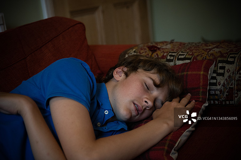 一个十几岁的男孩睡在沙发上图片素材