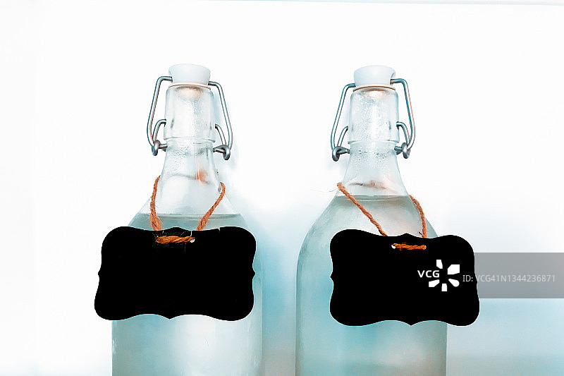 两个装满水的玻璃瓶，上面有空白的黑色标签图片素材