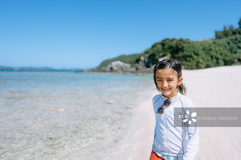 欢快的年轻女孩走在日本冲绳的热带海滩上图片素材