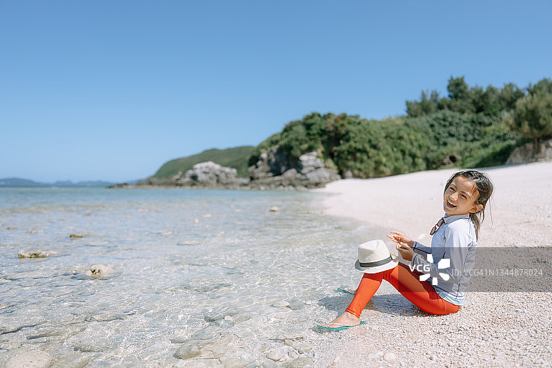 开朗的年轻女孩坐在海滩上，克拉马群岛，日本冲绳图片素材
