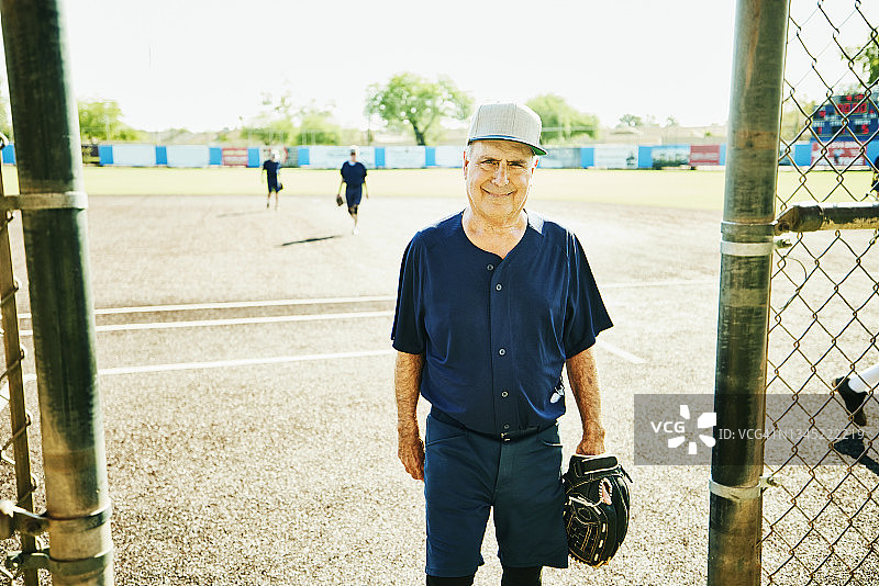 在夏季的早晨，一名高中垒球运动员微笑着站在休息区外的中宽照片图片素材