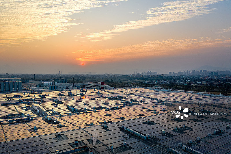 日落时工厂屋顶太阳能电池板的鸟瞰图图片素材