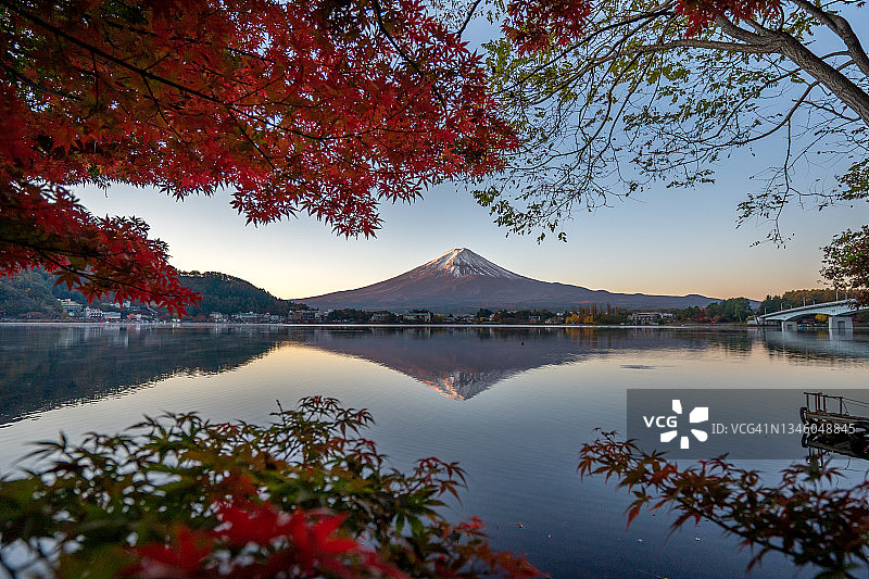 富士山倒影在水与生机勃勃的秋天树叶颜色前景在湖川口，日本秋天季节。图片素材