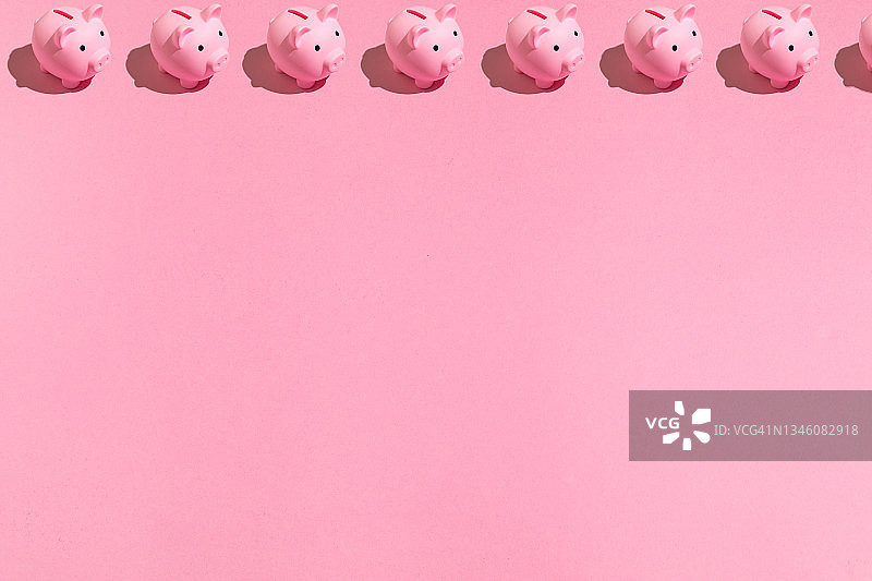 图案粉红色的小猪储蓄罐与黑色的眼睛，在上面，复制空间，在粉红色的背景。存钱的观念，省钱的观念。图片素材