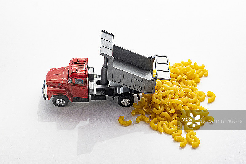 红色玩具卡车倾倒一堆手肘通心粉在白色背景-系列的一部分图片素材